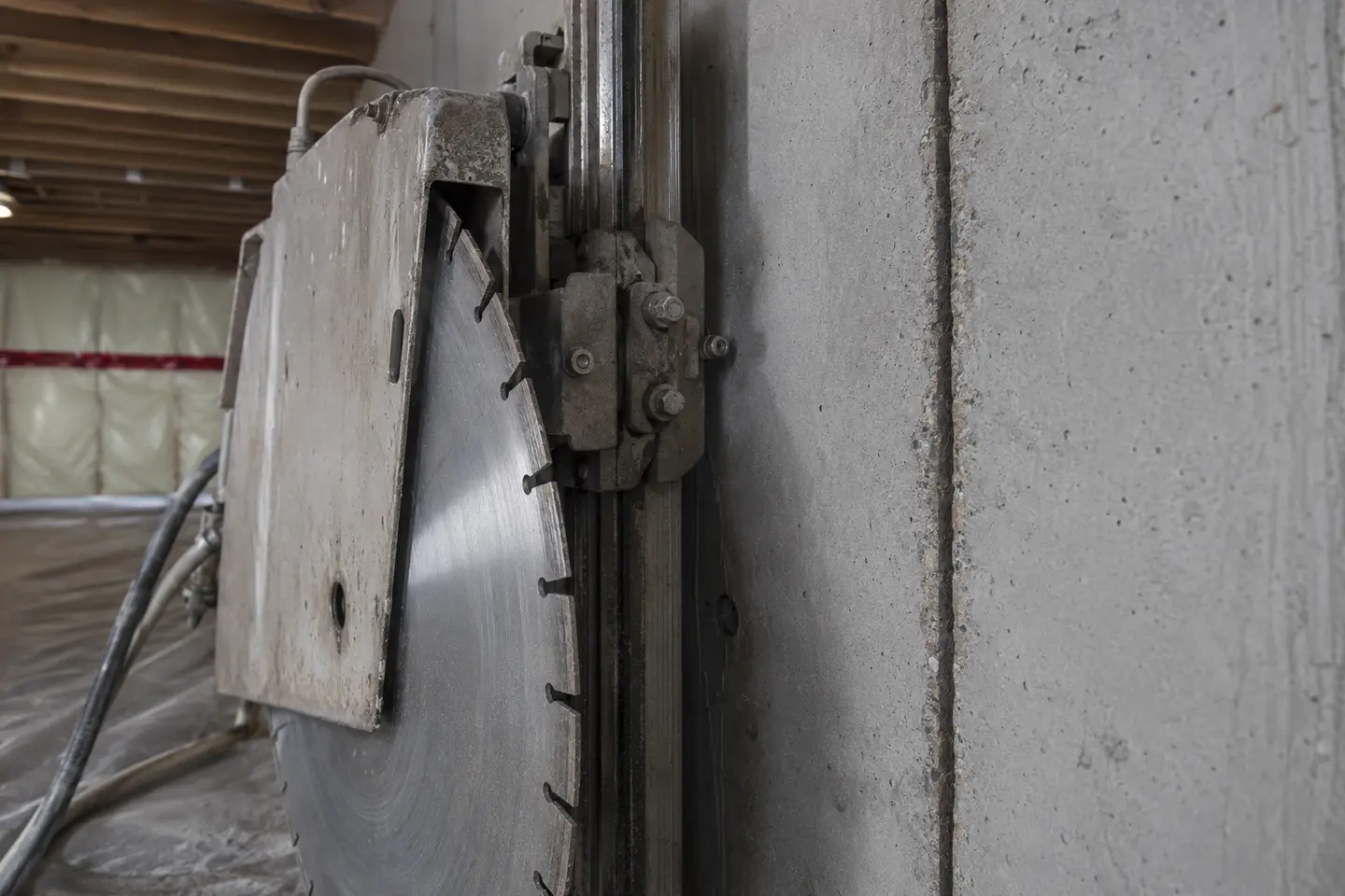 Close-up of an inactive diamond wall-saw blade aligned beside a crisp vertical cut in poured residential concrete